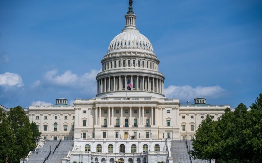 A frontal view of the iconic US Capitol Building in Washington D.C. under blue skies.
