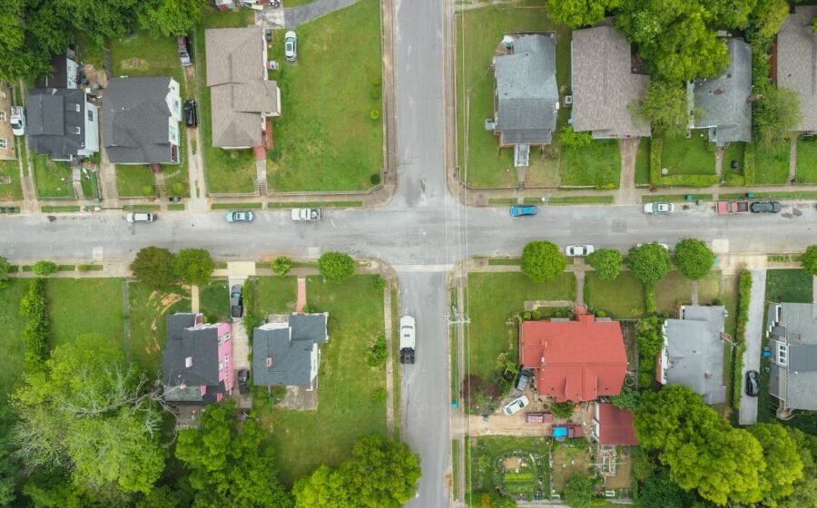 Aerial photo capturing an intersection in a suburban neighborhood with houses and greenery.